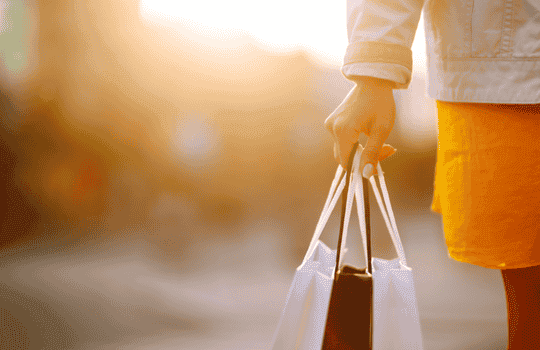 Person carrying shopping bags in warm orange light.