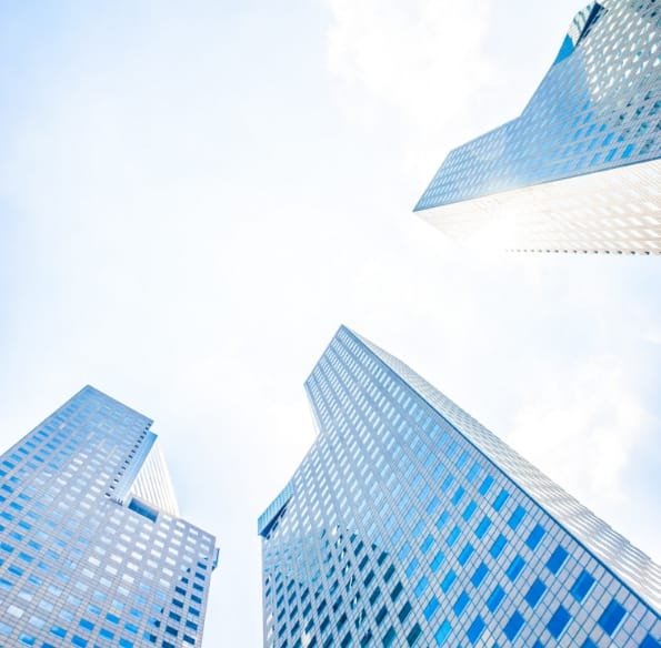 Modern office buildings viewed from below against a bright sky.